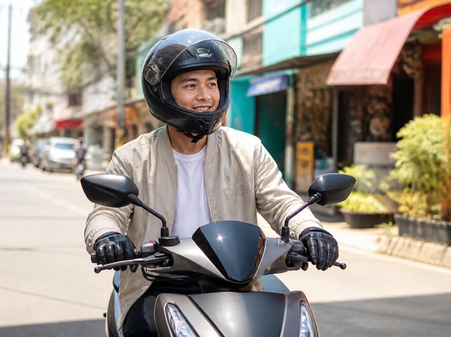 A smiling young rider on a scooter in a sunny city street